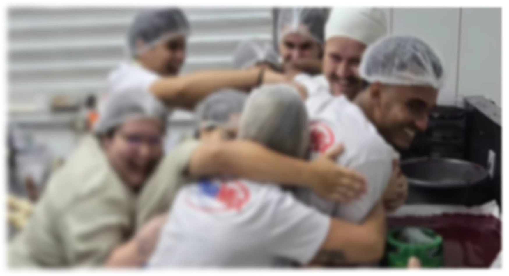 Equipe do Megamix se abraçando e sorrindo na cozinha de produção da loja